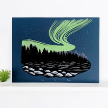 Load image into Gallery viewer, Northern lights artwork. A rich neon green aurora ink on top of a dark blue backround behind the shadows of a Black Forest. A lake in the foreground showing some light on rocks.  Aurora Borealis front
